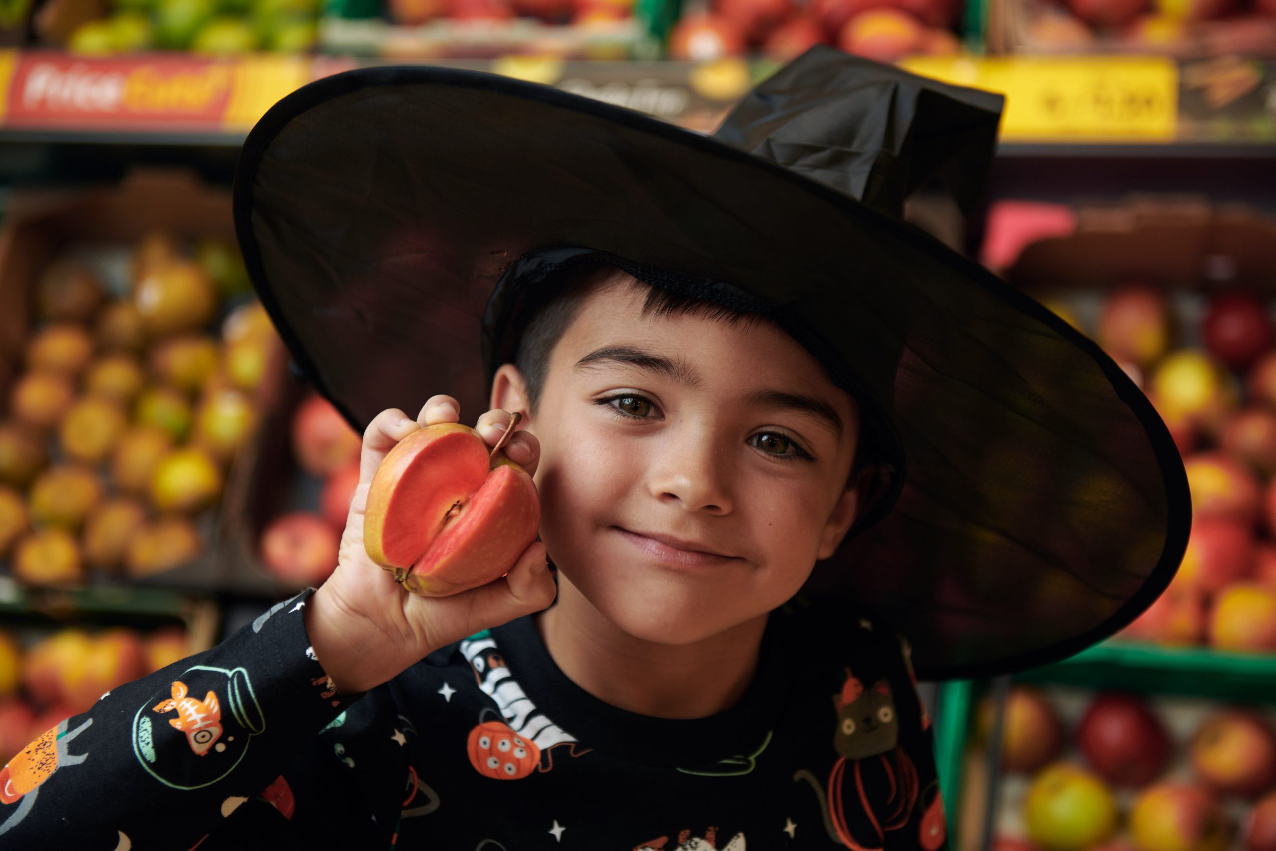 Promotion campaigns made by Morrisons with Kissabel apples. A child holding an appel, dressed like a wizard, in a retail store. Copyright: Morrisons.