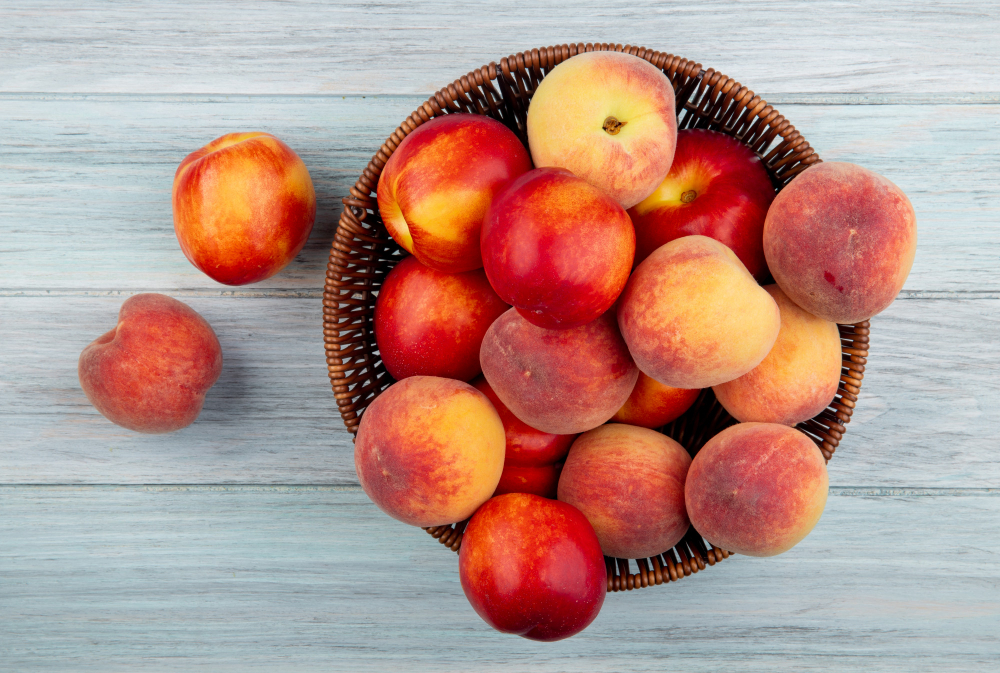 top view fresh ripe nectarines peaches wicker basket grey background. Copyright Stoccking/Freepik